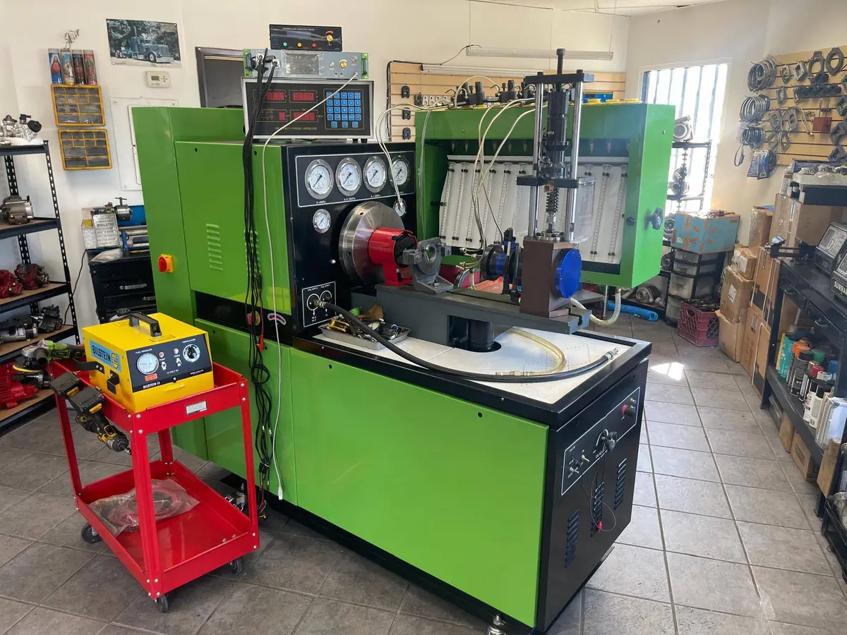 Injector flow-test bench at Bedrosean Repair — gauges, control panel, and glass measuring cylinders where customers watch their injectors tested