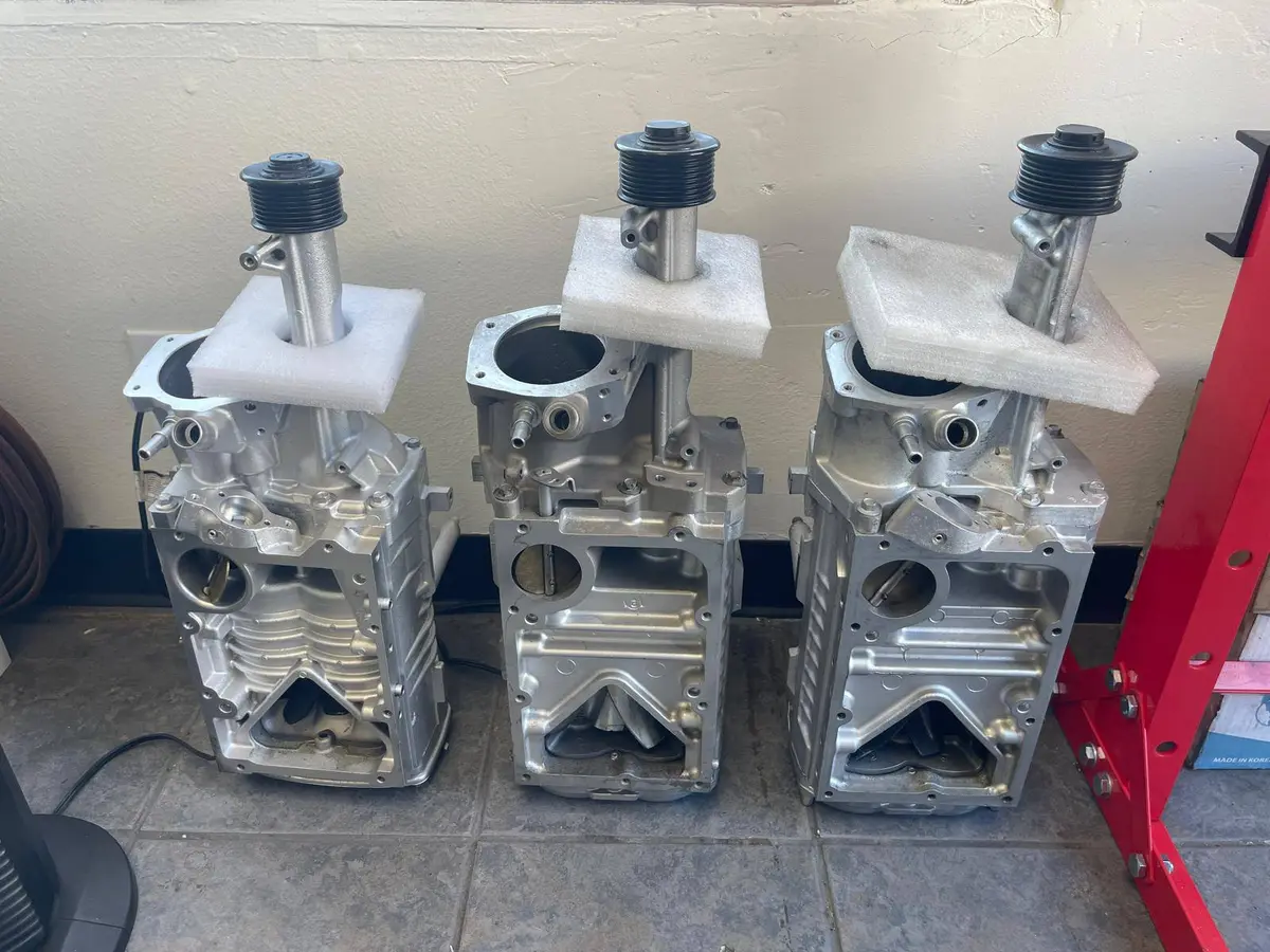 Three rebuilt roots-type superchargers lined up after rotor pack and seal service